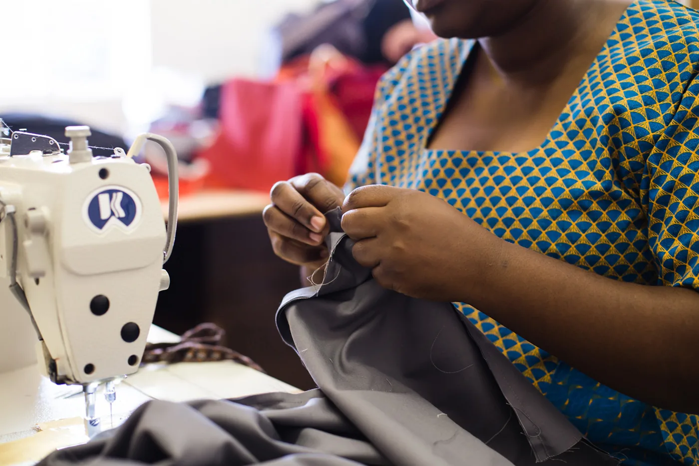 Seamstress in a shweshwe dress sewing a bag at the Local Conference Solutions workshop